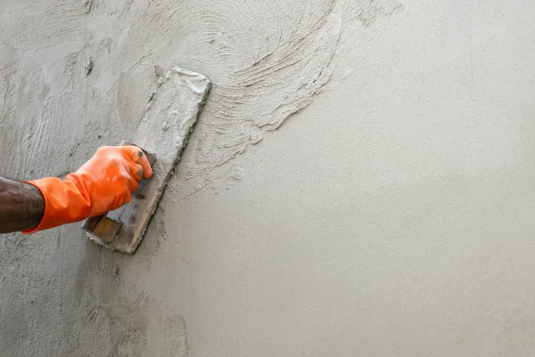 Gloved hand smoothing fresh parging with a trowel