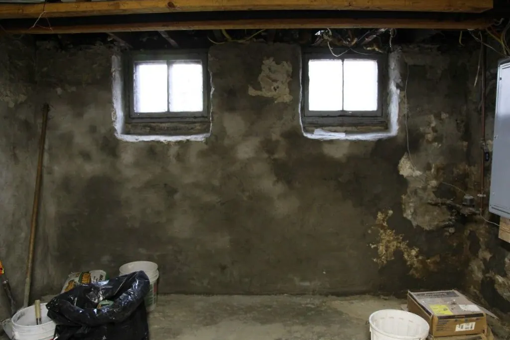 Old stone basement wall with a parge coat and white returns around two windows