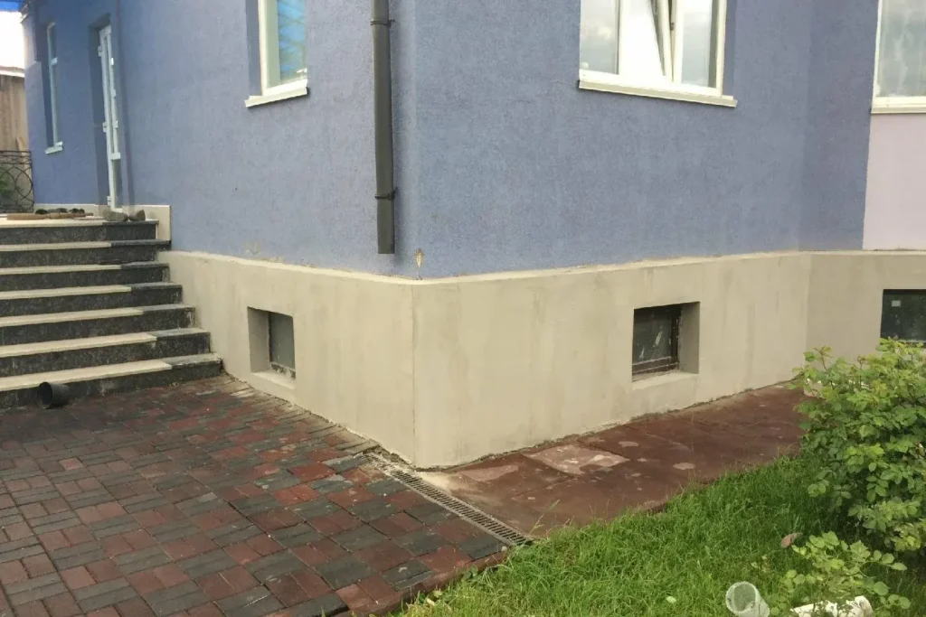 Fresh grey parging on a raised foundation around basement windows