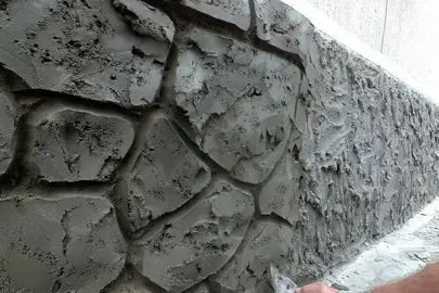 Hand carving a stone pattern into fresh parging