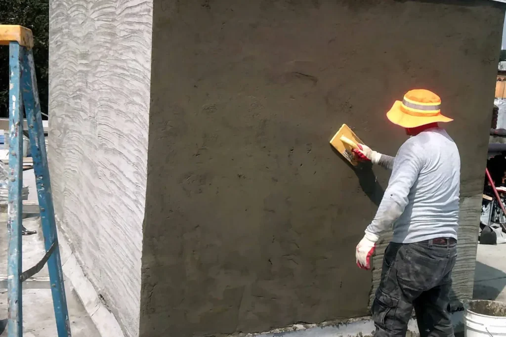 Worker finishing a fresh cement coat on a wall with a sponge float