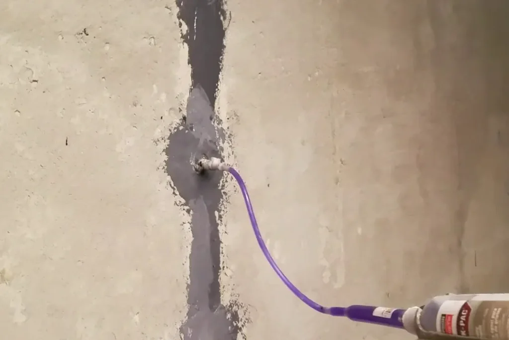 Injection tube filling a sealed crack in a poured concrete foundation wall