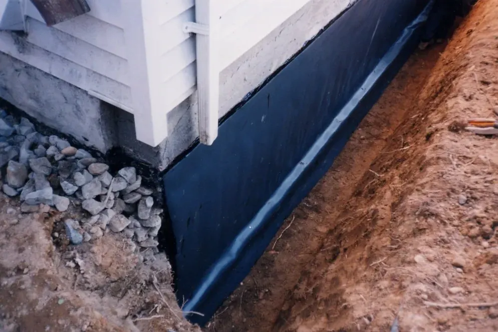Black waterproofing membrane on a foundation in an open trench