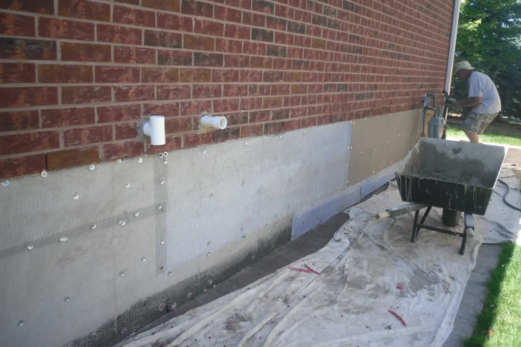 Wire mesh fastened to a foundation below brick, ready for a new parge coat