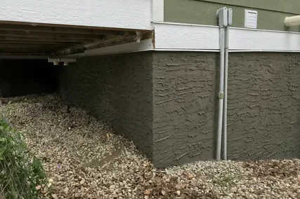 Textured parging on a foundation under a wooden deck